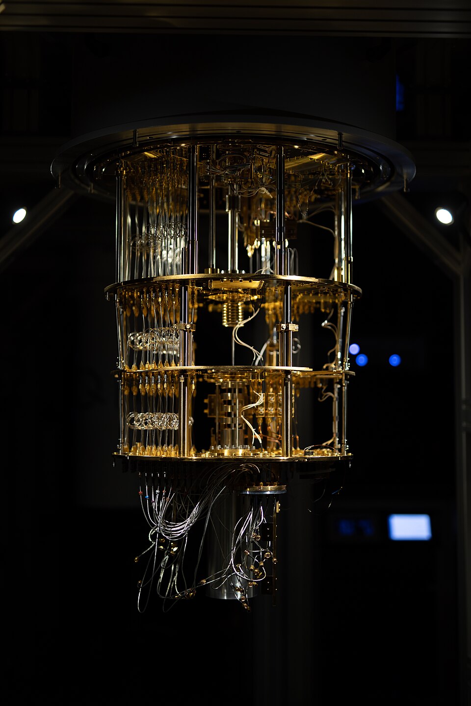 A gold, multi-tiered dilution refrigerator hanging open, with coaxial cables running down through its plates