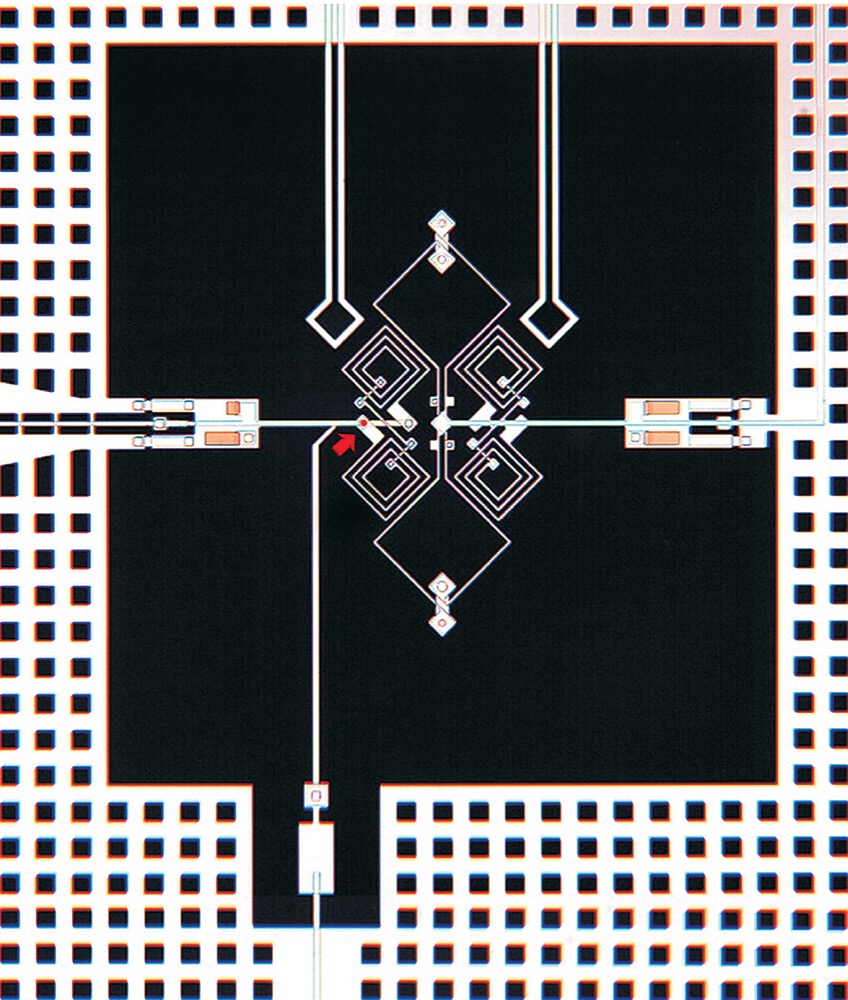 Microscope image of a superconducting qubit: white metal lines on black, a red arrow pointing at the Josephson junction, and a grid of square holes in the surrounding metal